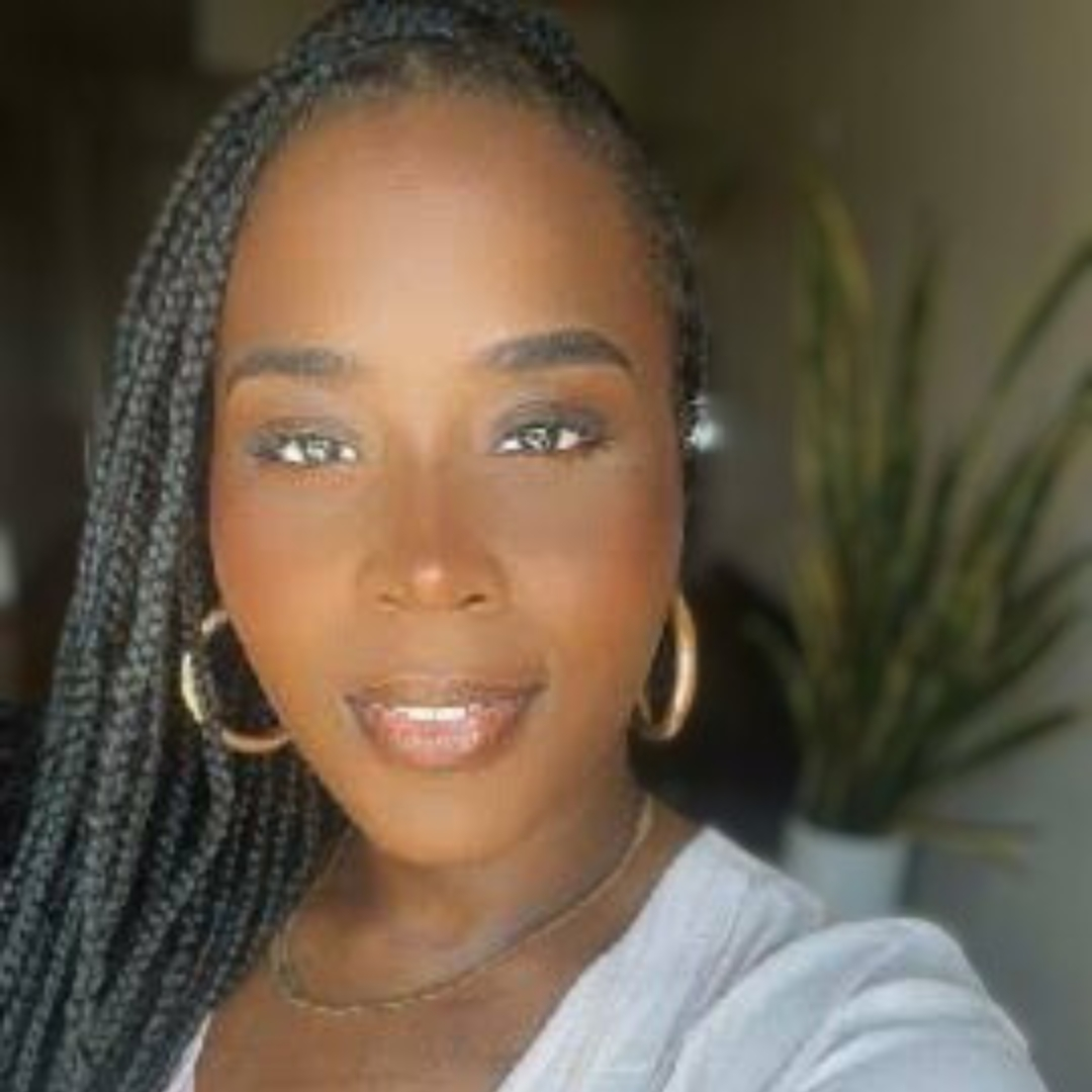 Vanessa, A dark brown skinned woman with braids smiles at the camera